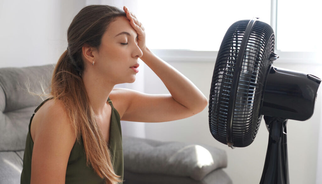 woman in front of fan due to hvac system in need of repair