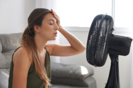 woman in front of fan due to hvac system in need of repair