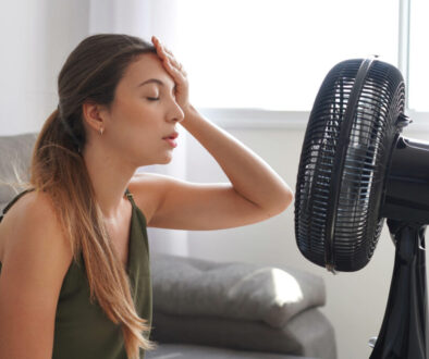 woman in front of fan due to hvac system in need of repair