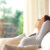 Young woman sitting on her couch, breathing deeply and enjoying the quality of the air in her home thanks to following the tips in this blog